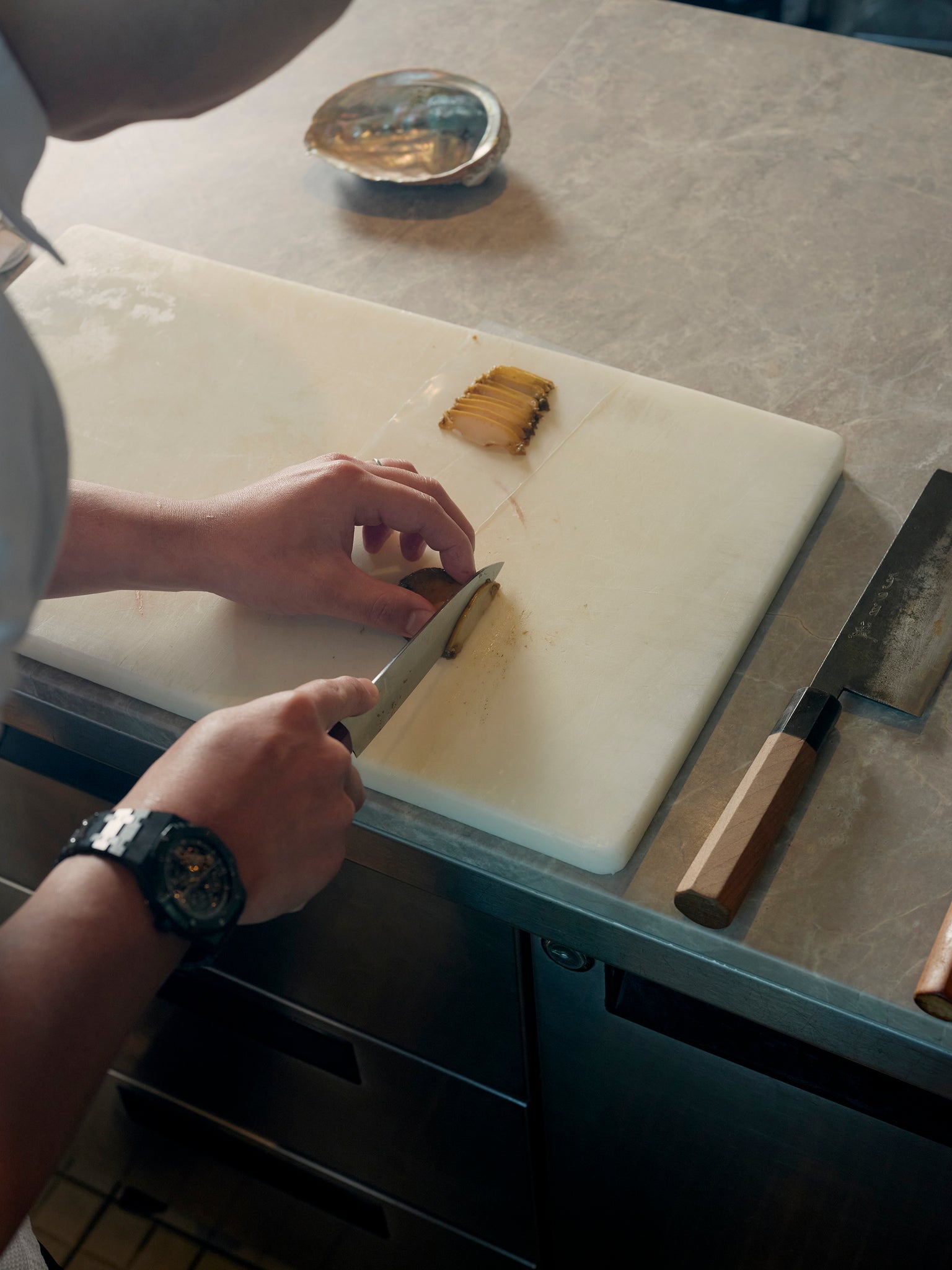 Vicky Cheng, chef and co-owner of Wing Restaurant with sliced abalone placed on a white chopping board with an abalone shell at the side, traditional Chinese cooking interview by A Collected Man London